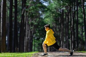 Piste coureur est élongation pour chaud en haut Extérieur dans le pin forêt saleté route pour exercice et faire des exercices Activités formation pour réalisation en bonne santé mode de vie et aptitude usage photo