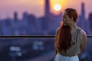 brunette femme est pleurs à le balcon pendant le coucher du soleil avec paysage urbain vue pour ptsd et la dépression de le rupture en haut photo