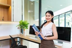 asiatique femme d'affaires dans formel affaires vêtements travail dans moderne luxe Bureau en portant dossier document pour affaires et éducation photo