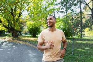 de bonne humeur et réussi hispanique homme le jogging dans le parc, homme fonctionnement sur une ensoleillé jour, souriant et content ayant un Extérieur activité. photo