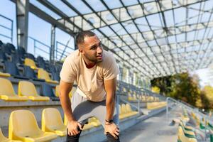 fatigué hispanique athlète courbé plus de et respiration après jogging, homme Faire des sports sur ensoleillé journée avec actif des exercices et aptitude, athlète repos après jogging. photo