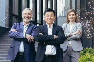 portrait de réussi et content asiatique patron avec le sien diverse rêver équipe, affaires gens à l'extérieur Bureau bâtiment permanent avec bras franchi et à la recherche à caméra photo