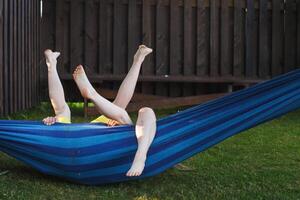 des enfants heureux se détendent dans un hamac en plein air. pieds nus des enfants. vacances vacances photo