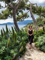 magnifique Jeune femme dans une élégant robe élégamment pose près le bassin à une luxueux villa photo