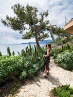 magnifique Jeune femme dans une élégant robe élégamment pose près le bassin à une luxueux villa photo