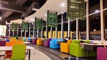 le atmosphère de une nourriture tribunal ou restaurant dans une achats centre commercial ou place avec coloré chaises, Indonésie, 25 Mars 2024. photo