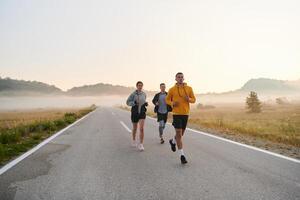 une groupe de amis, les athlètes, et joggeurs embrasse le de bonne heure Matin heures comme elles ou ils courir par le brumeux aube, excité par le en hausse Soleil et entouré par le tranquille beauté de la nature photo