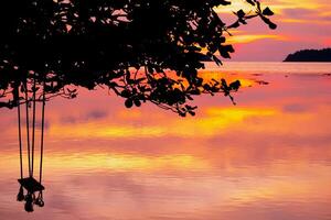 bois balançoire magnifique le coucher du soleil sur le mer Contexte photo