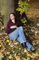 Jeune femme en train de dormir en dessous de une arbre dans l'automne photo