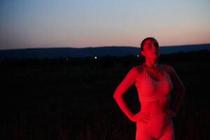 athlète grèves une pose dans allumé en rouge la nuit lueur photo