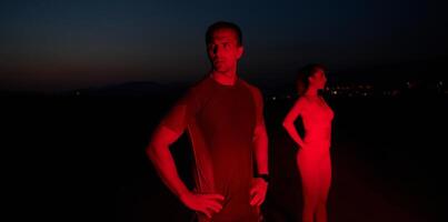 athlète grèves une pose en dessous de rouge la nuit lueur après intense toute la journée marathon. photo