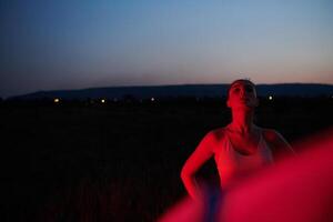 athlète grèves une pose dans allumé en rouge la nuit lueur photo