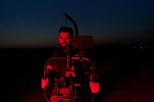 la nuit capture. professionnel vidéaste films les athlètes fonctionnement dans allumé en rouge obscurité photo