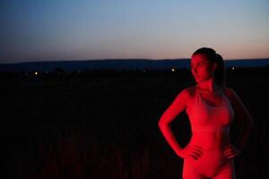 athlète grèves une pose dans allumé en rouge la nuit lueur photo