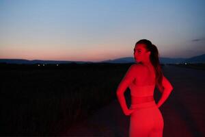 athlète grèves une pose dans allumé en rouge la nuit lueur photo