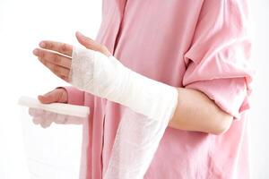 une femme dans une rose chemise détient une bandage et met une bandage sur sa bras. photo