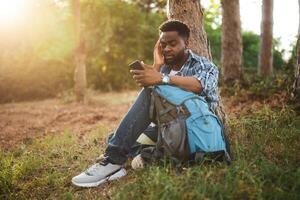 inquiet promeneur eu perdu et il est en utilisant une téléphone à trouver droite direction tandis que séance dans le la nature. photo