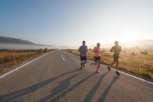 une groupe de amis, les athlètes, et joggeurs embrasse le de bonne heure Matin heures comme elles ou ils courir par le brumeux aube, excité par le en hausse Soleil et entouré par le tranquille beauté de la nature photo