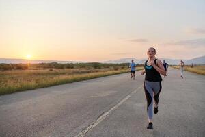 une diverse groupe de coureurs les trains ensemble à le coucher du soleil. photo