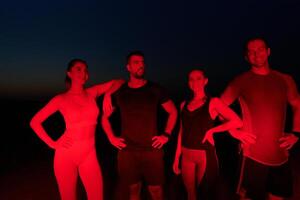 diverse les athlètes se détendre. post-marathon du repos en dessous de rouge la nuit briller. photo