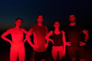 diverse les athlètes se détendre. post-marathon du repos en dessous de rouge la nuit briller. photo