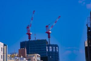 grue à le en dessous de construction derrière le bleu ciel dans tokyo photo