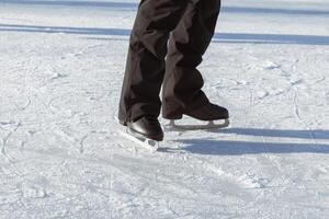 Pour des hommes jambes dans noir patins fermer sur le patinoire. Aller pour une conduire. actif hiver vacances photo