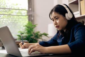 Créatif Jeune étudiant les usages une portable à Achevée en ligne devoirs pour Université et Université cours. femme études une livre et conduit recherche pour en ligne académie en utilisant portable dans bureau. photo