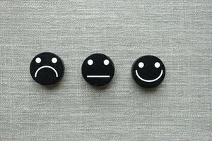 content, neutre et triste visages sur noir en bois blocs. client la satisfaction ou évaluation concept photo