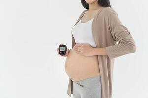 Enceinte femme vérification du sang sucre niveau par en utilisant numérique glucose mètre, santé se soucier, médecine, diabète, glycémie concept photo