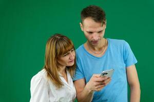 téléphone appel chercher sur le l'Internet à résoudre problèmes une homme aide une femme sur une vert Contexte chromakey dépenser temps dans Bureau dans la nature bleu T-shirt blanc veste lumière gens pavé tactile nouvelles alimentation gadget photo