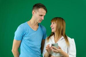 téléphone appel chercher sur le l'Internet à résoudre problèmes une homme aide une femme sur une vert Contexte chromakey dépenser temps dans Bureau dans la nature bleu T-shirt blanc veste lumière gens pavé tactile nouvelles alimentation gadget photo