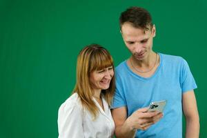 téléphone appel chercher sur le l'Internet à résoudre problèmes une homme aide une femme sur une vert Contexte chromakey dépenser temps dans Bureau dans la nature bleu T-shirt blanc veste lumière gens pavé tactile nouvelles alimentation gadget photo