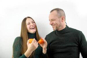 content en riant couple embrasser dans slowmo parlant et peeling mandarines. Enceinte caucasien épouse et souriant mari profiter Noël fête à Accueil à l'intérieur. photo