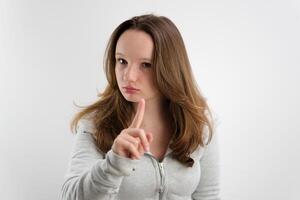 Jeune magnifique fille adolescent élevé sa indice doigt en haut alerte pense être attentif avoir un idée Ecoutez à moi elle porte une survêtement sur une blanc Contexte européen marron cheveux photo