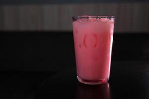 fraise Lait dans une verre avec rayé papier paille isolé sur une noir Contexte photo