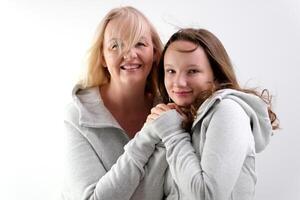 magnifique gens deux femmes mère et fille Regardez dans le Cadre et puis à chaque autre sourire tendresse identique vêtements des modèles sur blanc Contexte dans studio rire sourire toucher nez à votre joue photo