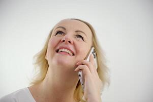 femme content joyeusement jeta sa tête en haut parlant sur le téléphone avec plaisir félicité agréable émotions et magnifique les dents mignonne âge moyen femme dans studio blanc Contexte La publicité comme une sincère sourire photo