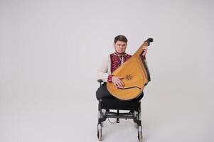 ukrainien cosaque jouer harpe Beau Jeune homme avec kobza musical instrument dans mains est assis sur blanc Contexte guerre vétéran habillé dans ukrainien brodé chemise nationale symboles de Ukraine vyshyvanka photo