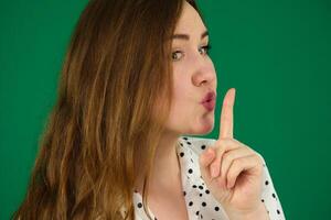 Jeune content femme montrant silence signe avec doigt plus de lèvres plus de vert écran photo