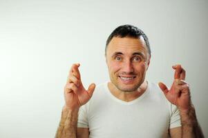 homme fait du souhait pour il à viens vrai près visage sur tous les deux côtés met deux mains avec les doigts franchi lorsque une la personne trompe il aussi des croix le sien les doigts sourire non naturel joyeux timide excuse moi âge moyen homme photo