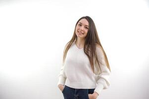 portrait de Jeune content magnifique femme souriant et permanent isolé sur blanc Contexte dans une chaud chandail. Jeune femelle fille avec une parfait sourire à la recherche droite. photo