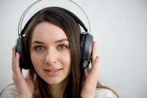 fermer portrait de charmant Jeune femme profiter la musique en utilisant écouteurs, isolé plus de blanc photo