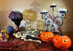 Halloween décorations chandelier sur table enveloppé dans toiles d'araignées de tout côtés deux citrouilles sont clignotant proche noir vase dans il avec séché fleurs deux squelettes prendre selfie avec guêpes supporter sur livres photo