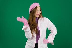 Jeune fille femme avec une rose béret sur sa tête France mode sur une vert Contexte chromakey. différent émotions rose veste gants longue marron cheveux. rose hiver l'automne tricoté gants sur mains photo