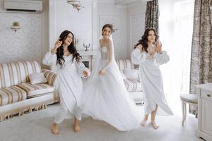 Trois femmes dans blanc Robes sont dansant dans une vivant pièce photo