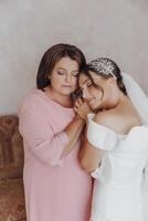 une mère câlins sa fille, le mariée, portant une mariage robe photo