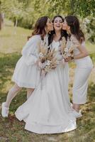 Trois femmes sont posant pour une image, un de leur est portant une blanc robe photo