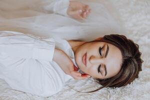 une femme est pose sur une lit avec sa tête sur sa main photo