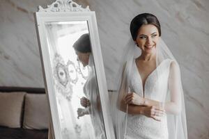 une femme est permanent dans de face de une miroir, portant une blanc robe et une voile photo